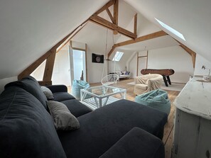Relax in this charming attic room with a sofa, coffee table, and hanging chair, perfect for unwinding and enjoying the view.