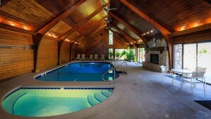 An indoor swimming pool with a wooden ceiling and stone walls.