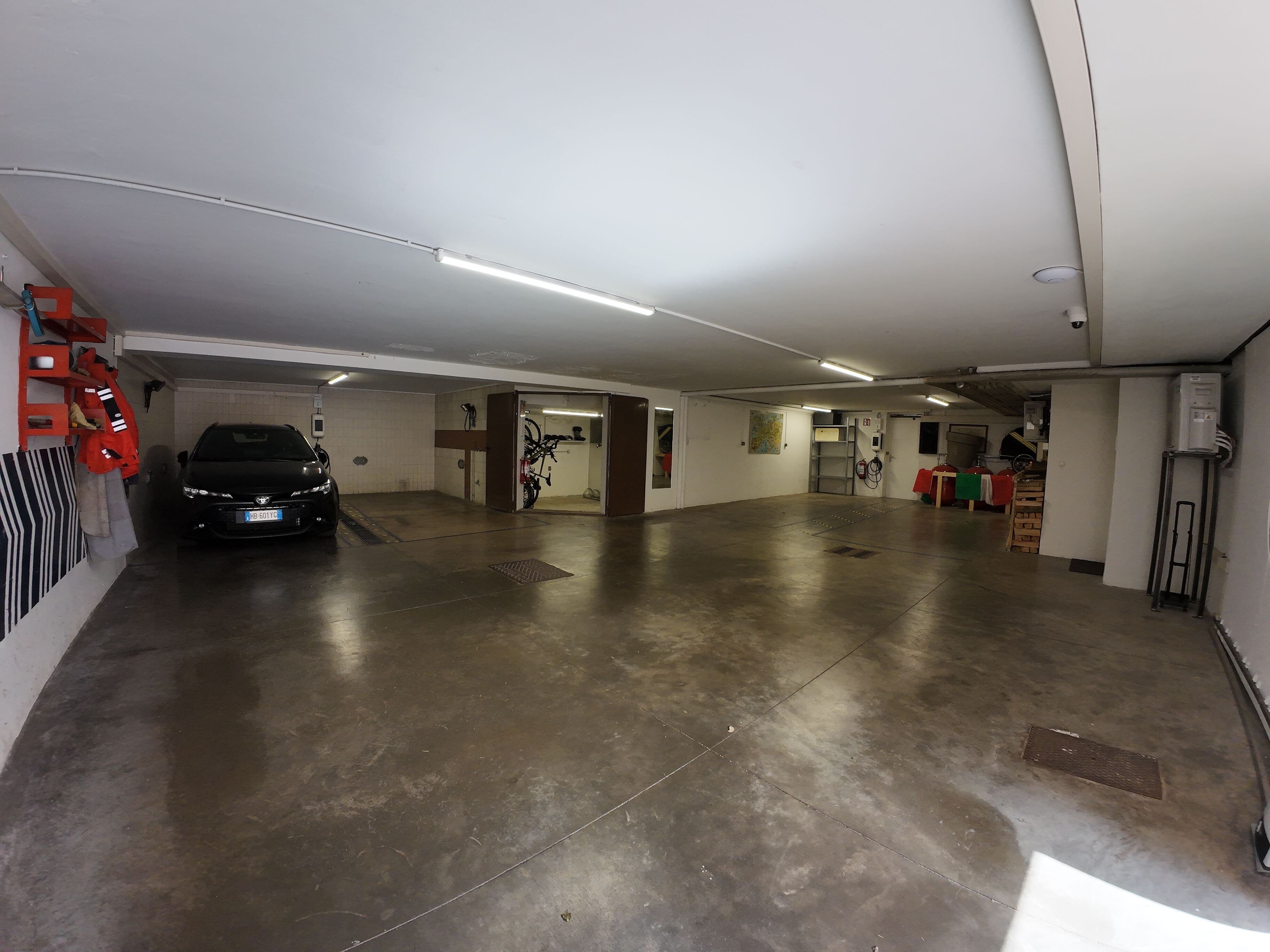Eine Parkgarage mit einem schwarzen Auto, das in der linken Spur geparkt ist, einem an der Wand montierten Feuerlöscher und einer Karte an der Wand.