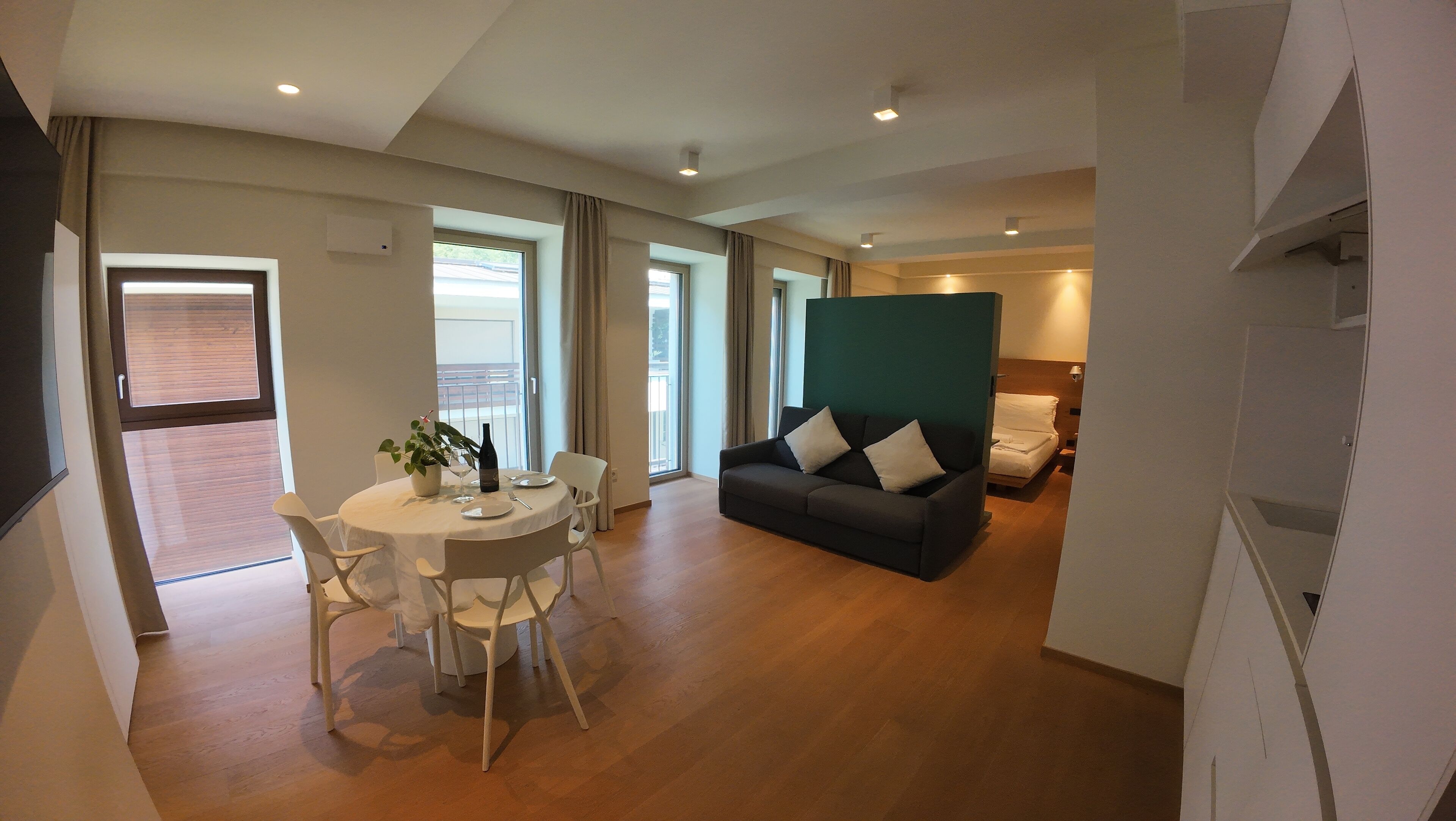 Ein modernes Wohnzimmer mit Essbereich, einer Couch und einem Bett.