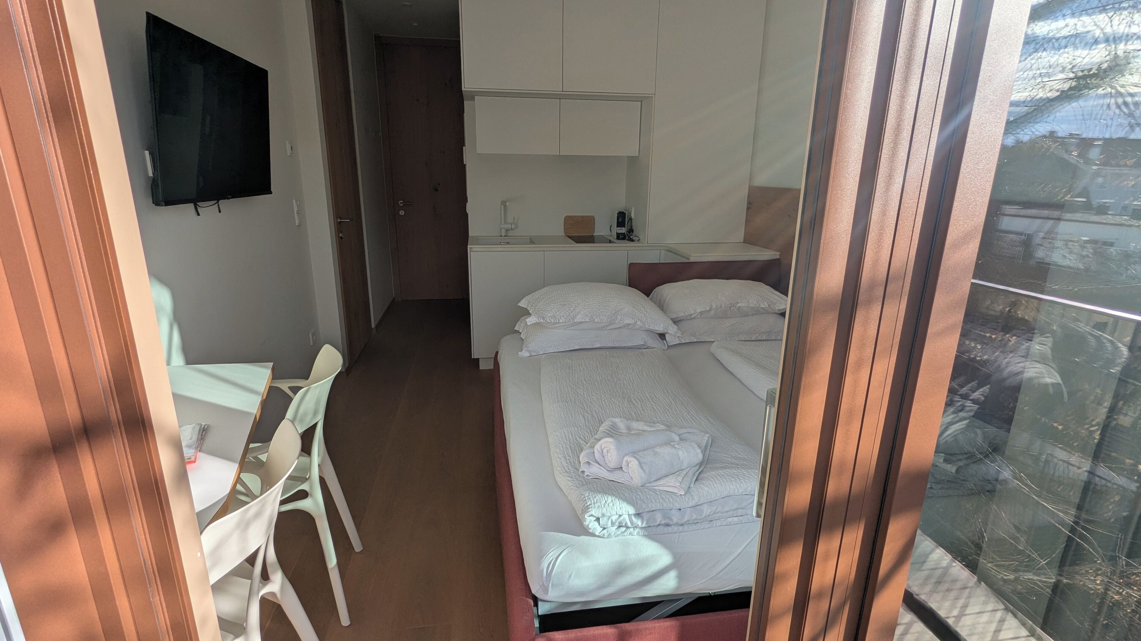 Una habitación de hotel con cama, escritorio, silla, televisor y baño.