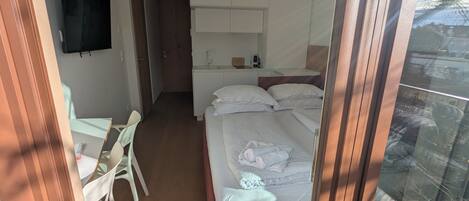 Una habitación de hotel con cama, escritorio, silla, televisor y baño.