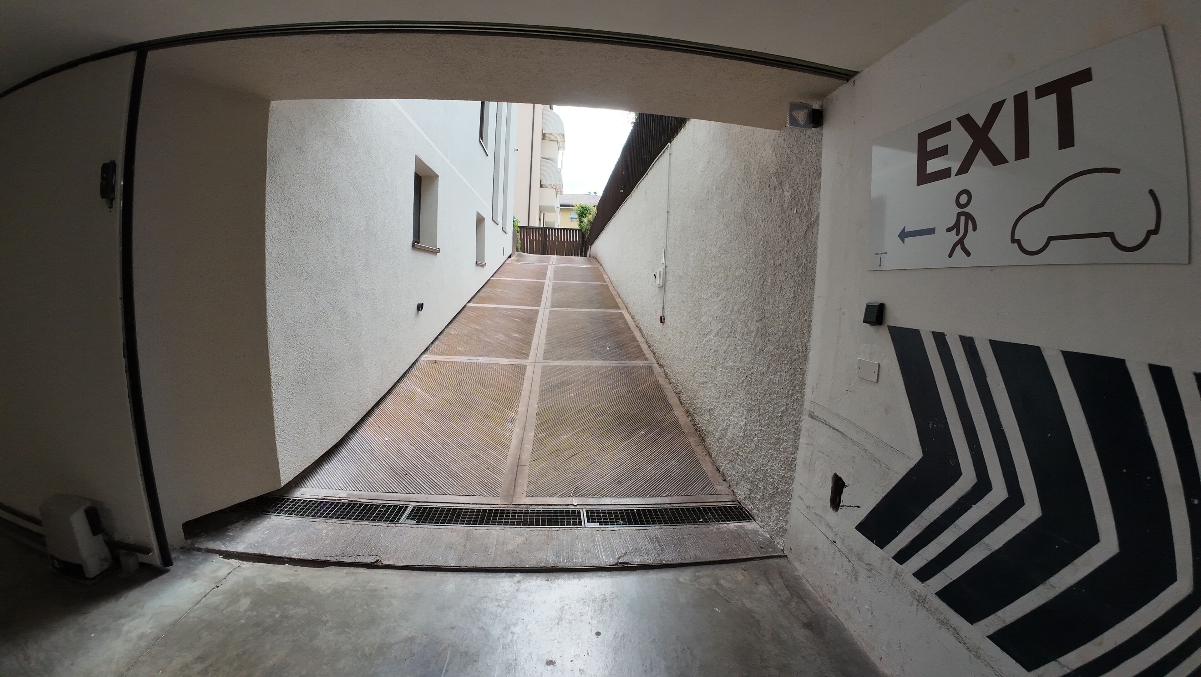 A corridor with an exit sign, a zebra-patterned floor, and a vent on the wall.