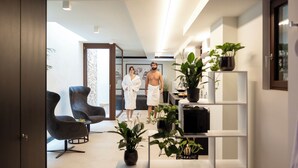 Un intérieur moderne avec un canapé, des fauteuils, un téléviseur et des plantes en pot.