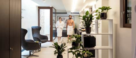Un interior moderno con sofá, sillas, televisor y plantas en macetas.