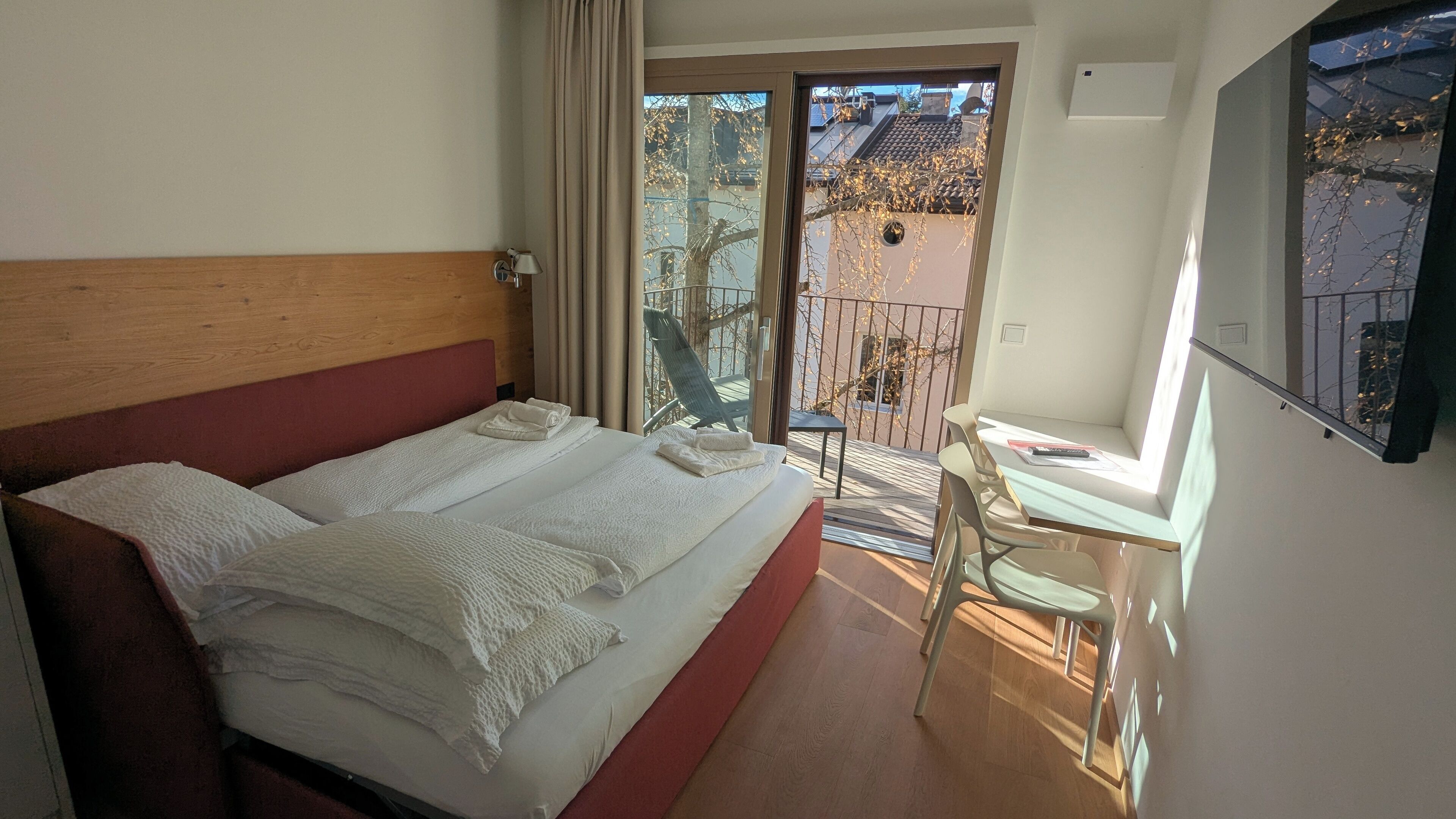 Une chambre d’hôtel avec un lit, une petite table, une chaise et un balcon donnant sur l’extérieur.