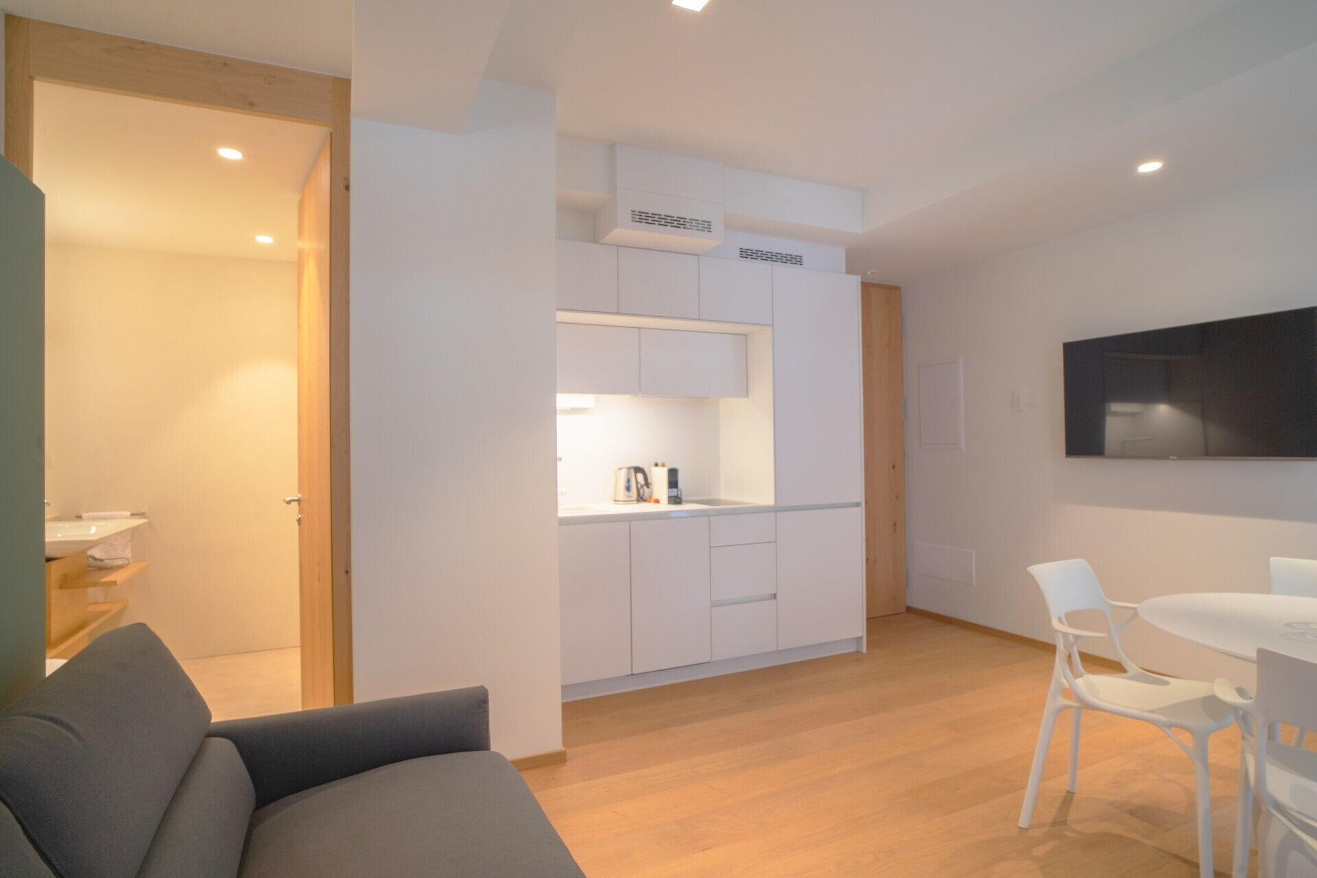 Ein modernes, kompaktes Wohnzimmer mit Küchenzeile, Essbereich und Sitzecke.