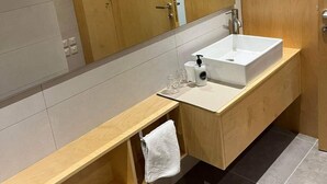 A modern bathroom with a wooden vanity, a large mirror, and a white sink. - Centrally located in Qawra, this modern 2-bed apartment offers comfort, style & easy access to the promenade — perfect for a carefree holiday escape! (San Pawl il-Baħar)