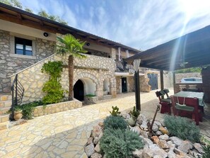A stone building with a covered patio area, outdoor seating, and a stone staircase. - Villa Paun (Vinodol)