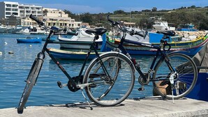 Een fiets geparkeerd aan het water, met boten op de achtergrond.