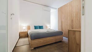 Een moderne slaapkamer met een houten bed, twee nachtkastjes met lampen en een houten kledingkast.
