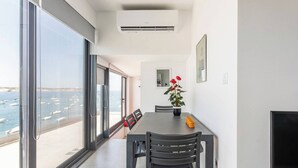 Un comedor moderno con vistas al mar, una planta en maceta y una mesa de comedor con sillas.