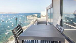 Un balcón con mesa y sillas que da a un puerto deportivo con numerosos barcos.
