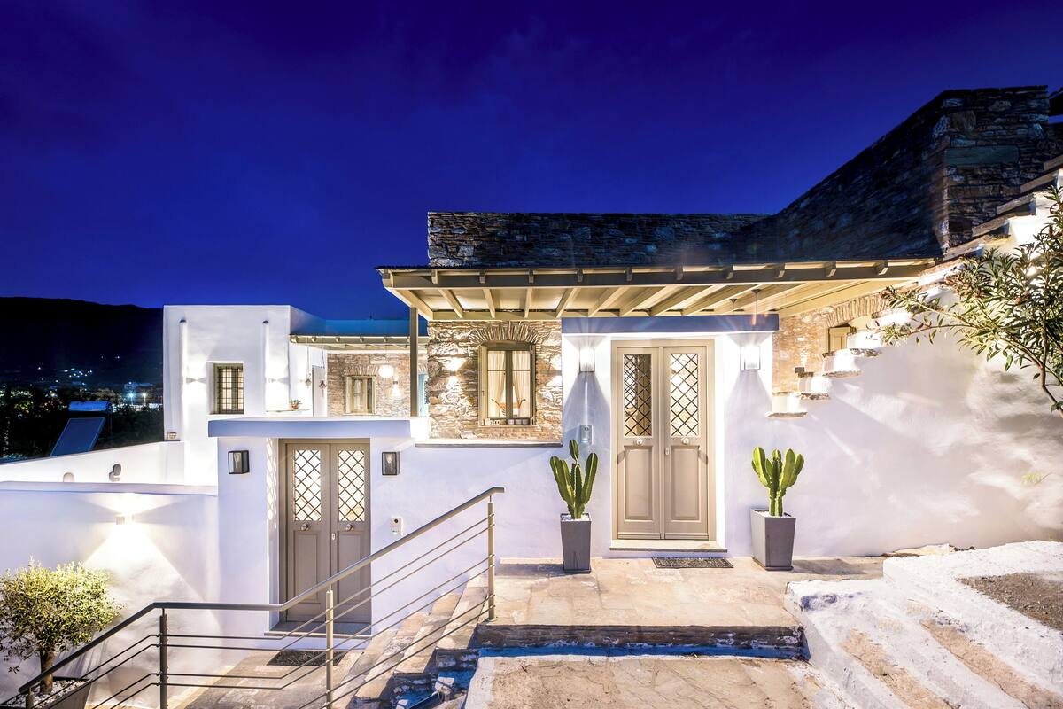 A modern house with a stone facade, a wooden door, and a staircase leading to a balcony.