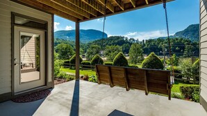 A porch with a swing overlooking a mountainous landscape.