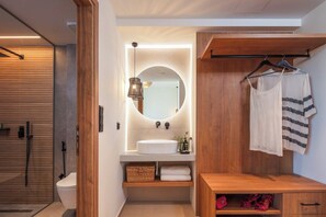 Un baño moderno con tocador de madera, espejo redondo, lavabo blanco y toallero colgante.