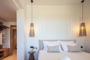 Ein Hotelzimmer mit einem großen Bett, zwei Pendelleuchten, einem Nachttisch mit einer Vase und einem Kleiderschrank.