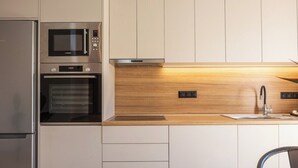 Una cocina moderna con electrodomésticos de acero inoxidable, encimera de madera y horno empotrado.