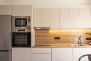 A modern kitchen with stainless steel appliances, a wooden countertop, and a built-in oven. - KaYa SeaView Residence (Bali)