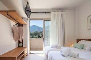 A bedroom with a bed, a TV, a wooden shelf, and a view of the outdoors. - KaYa SeaView Residence (Bali)
