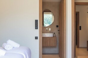 A modern bathroom with a freestanding sink, a mirror, and a wooden vanity. - KaYa SeaView Residence (Bali)