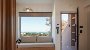 Una habitación moderna con un ventanal grande, un banco empotrado y una lámpara colgante.