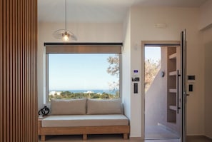 A modern room with a large window, a built-in bench, and a pendant light. - KaYa SeaView Residence (Bali)