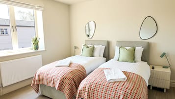 Une chambre d’hôtel avec deux lits, une fenêtre donnant sur un beau paysage, un radiateur et une table de chevet avec une lampe.