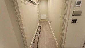 A narrow hallway with a radiator, a door, and a wall-mounted light fixture.