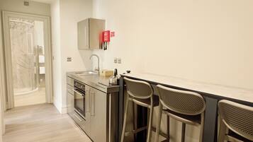 A modern kitchen with a built-in oven, a sink, and two bar stools.