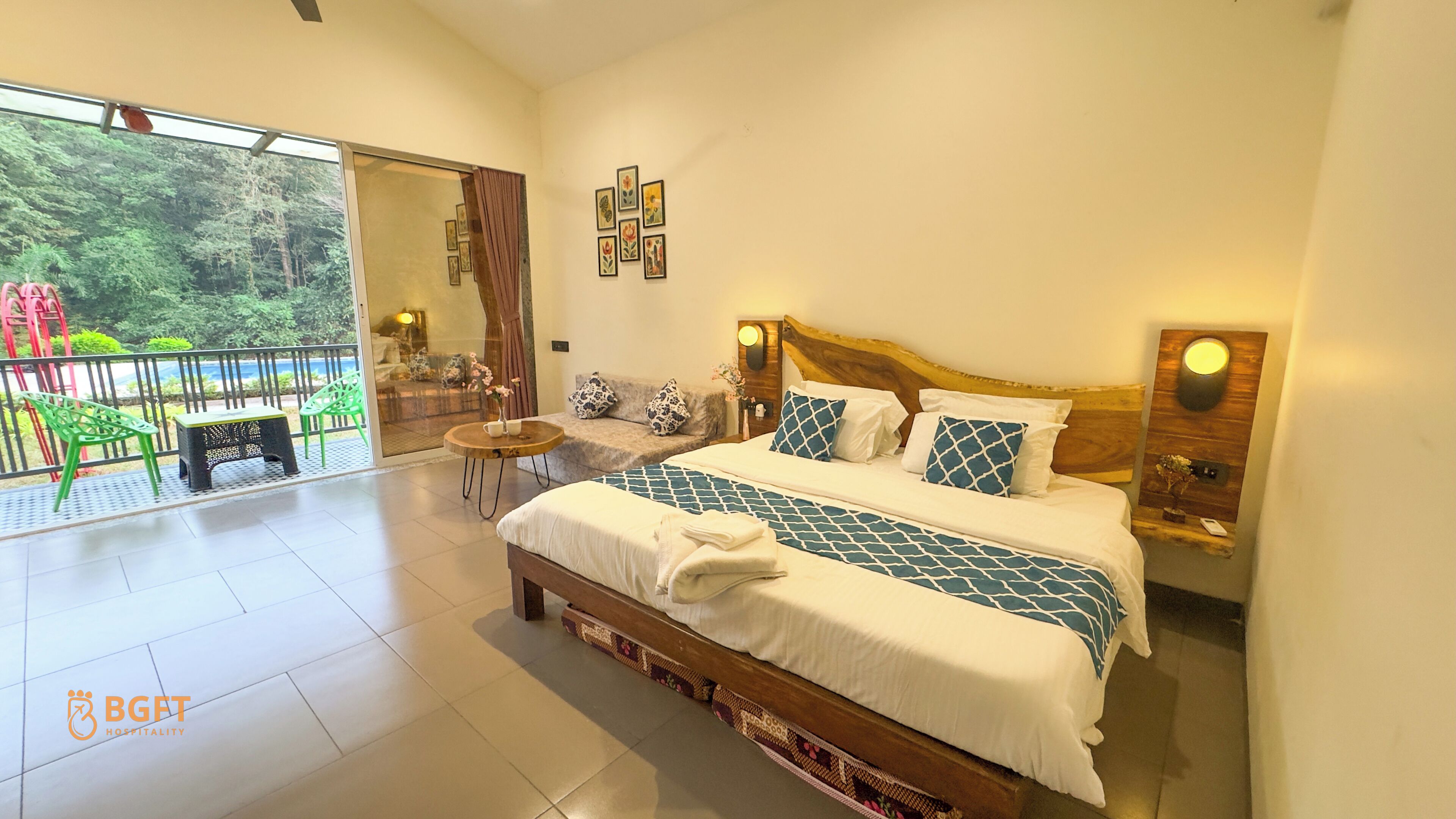 Een ruime slaapkamer met een groot bed, een klein tafeltje met een vaas, en uitzicht op een balkon met buitenmeubilair.