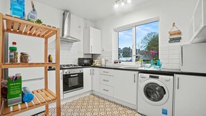 Eine moderne Küche mit weißen Schränken, einem Herd, Backofen, einer Mikrowelle und einer Waschmaschine.