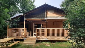 A wooden cabin with a covered porch, a small staircase, and a picnic table.