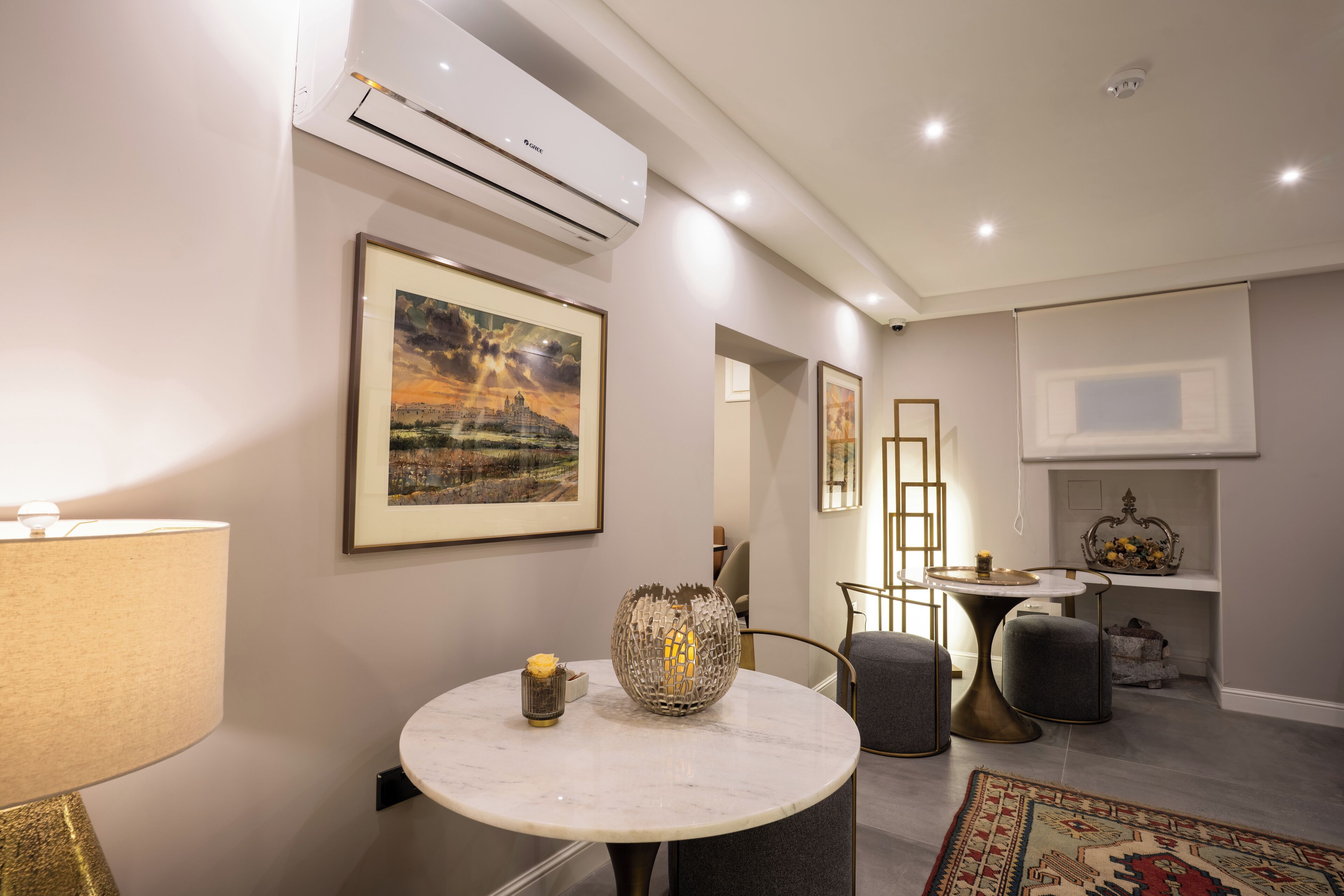 Een moderne woonkamer met een ronde marmeren tafel, een decoratieve lamp en een schilderij in een lijst aan de muur.