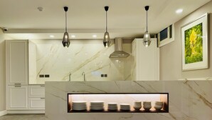 A modern kitchen with marble countertops, pendant lighting, and a built-in plate rack. - Howard House Hotel (Rabat)