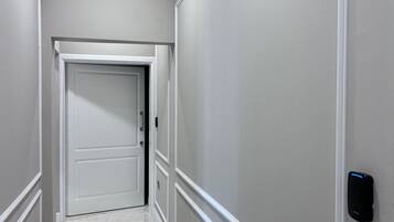A hallway with a marble floor, white walls, and a door at the end.