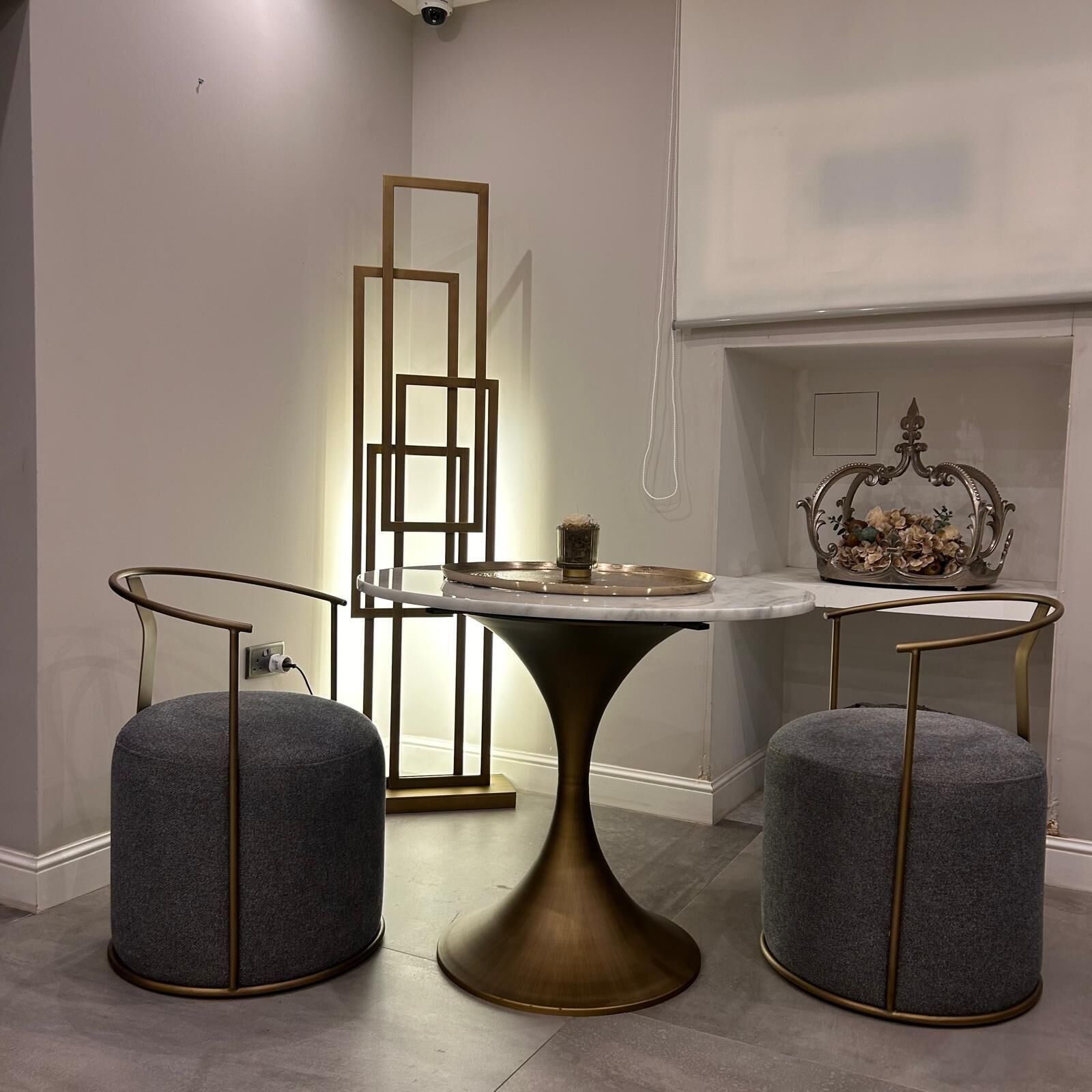 Un comedor moderno con una mesa central, dos taburetes y un espejo decorativo.