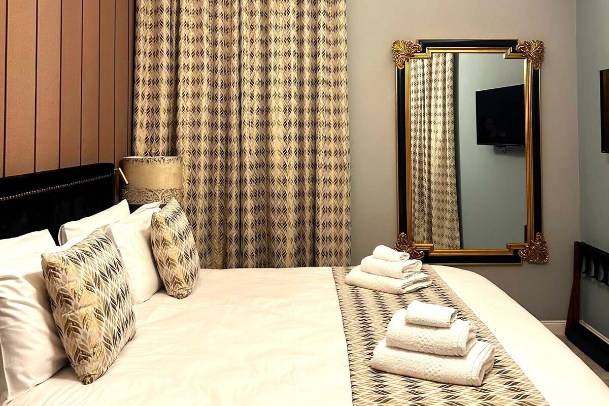 A hotel room with a bed, a large mirror, and a television.