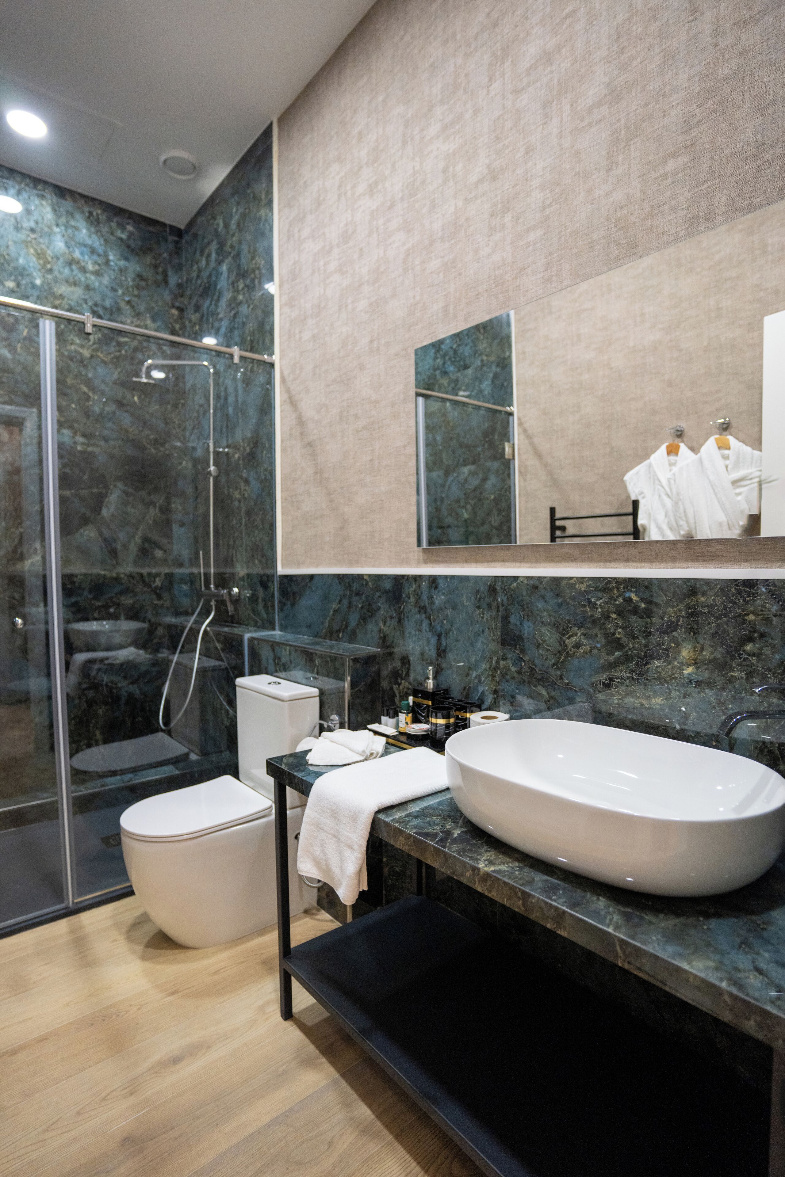 Une salle de bain moderne avec une douche à parois de verre, des toilettes blanches, une baignoire sur pieds et un comptoir en marbre.