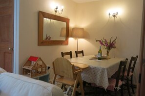 Uma área de refeições acolhedora com uma mesa posta para dois, uma luminária e um vaso com flores.