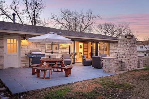 Un patio con una parrilla, mobiliario exterior y una chimenea de piedra.