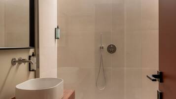 A modern bathroom with a glass-enclosed shower, a white sink, and a wooden vanity.