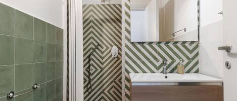 A bathroom with a shower, a sink, and a mirror.