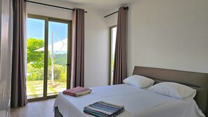 Un dormitorio con cama, cortinas y vistas a la vegetación.