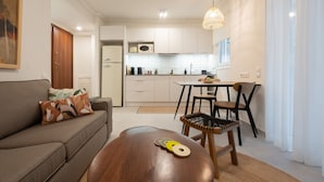 Een moderne woonkamer met een bank, een houten salontafel en een eethoek met stoelen.