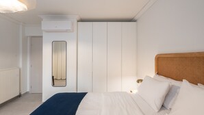 Een slaapkamer met een bed, witte muren, een spiegel, een kledingkast en een radiator.