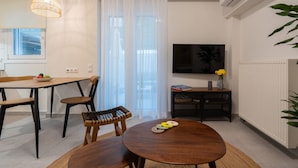 Een moderne woonkamer met een eettafel, stoelen, een televisie en een radiator.