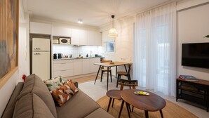 Een moderne woonkamer met een bank, een eettafel en een keuken op de achtergrond.