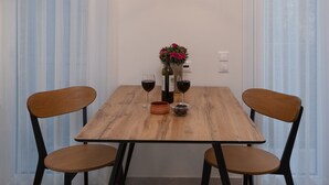 A dining area with a wooden table, four chairs, a hanging light fixture, and a vase with flowers. - Acropolis Walk • Starlink • Sunset Rooftop (Athens)