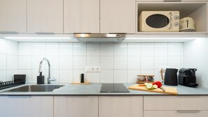 Et moderne køkken med stålvask, mikroovn og kaffemaskine.